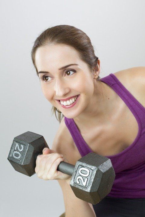 The girl with the dumbbells does exercises for weight loss